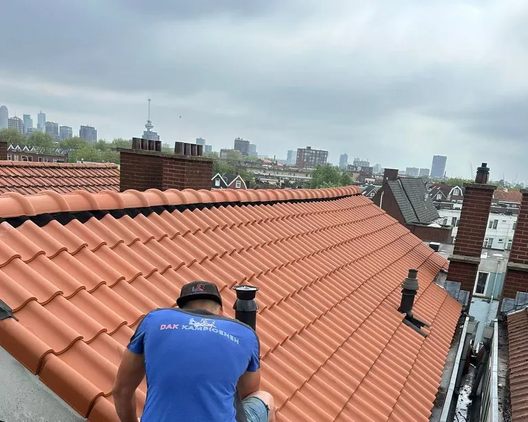 Dakdekker voert inspectie uit op dakpannen om verborgen lekkages vroegtijdig op te sporen.